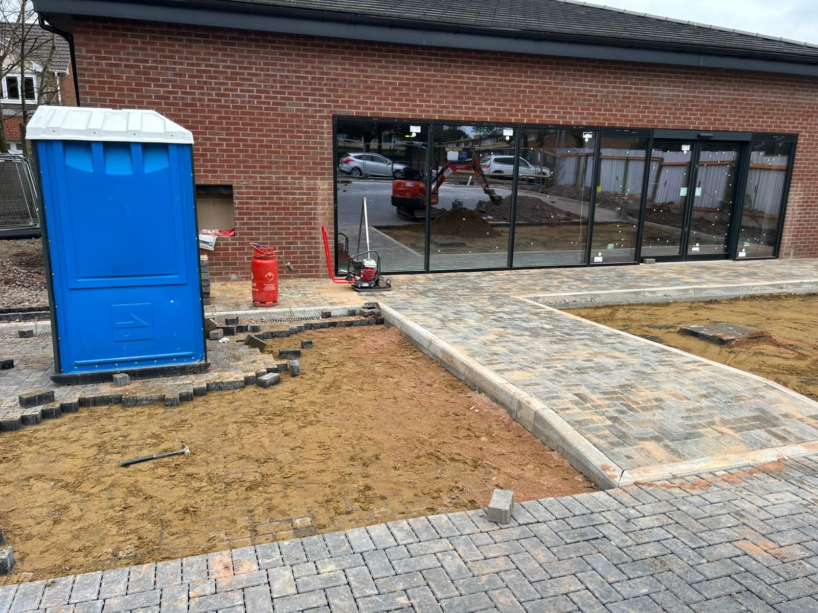 Block-paved path edged with kerbs, beside a new building