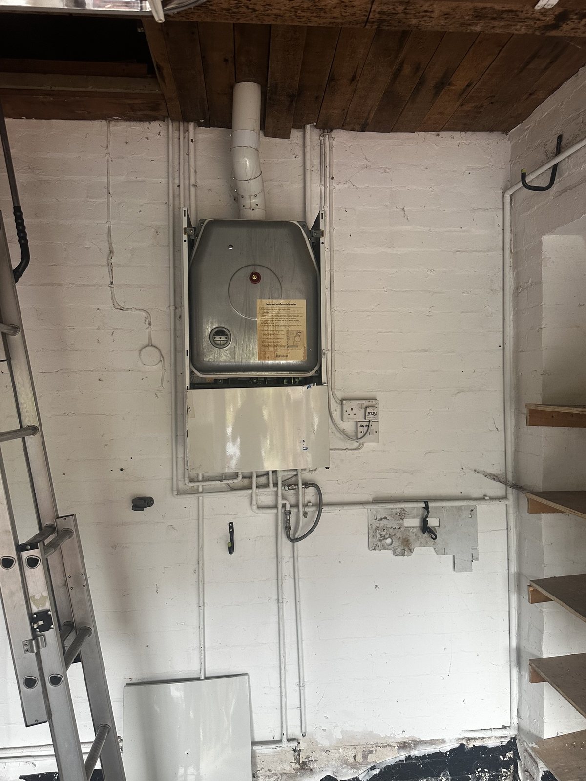 Wall-mounted gas boiler and flue in a plant room during heating works