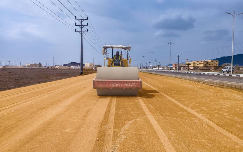 Ride-on roller compacting sub-base on a road construction site (illustrative stock photo)