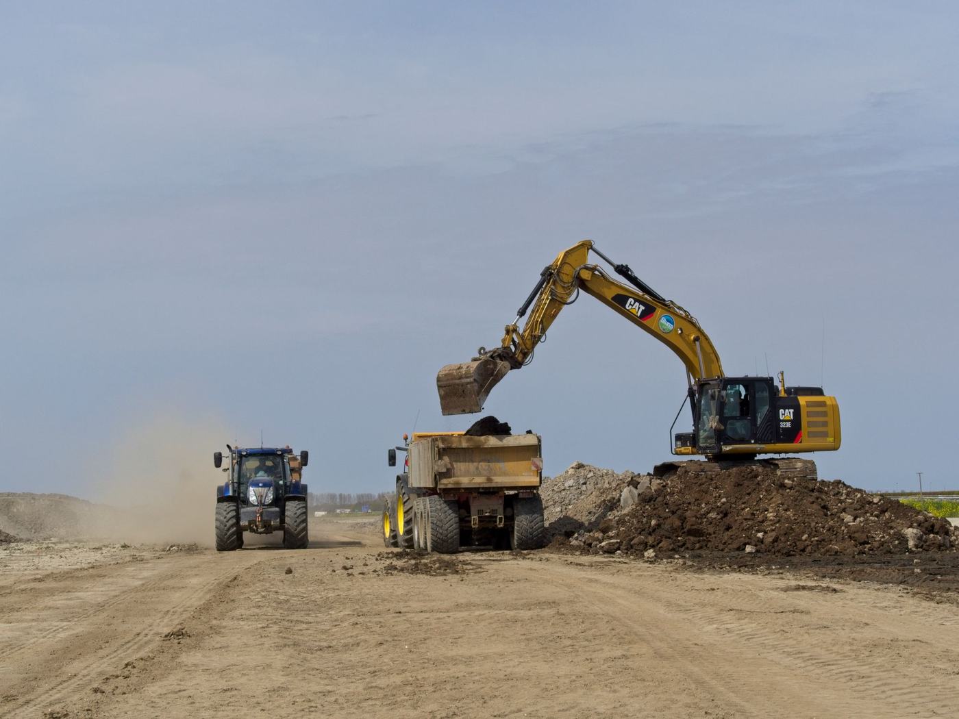 Tracked excavator loading a dumper during bulk earthmoving on a construction site (illustrative stock photo)
