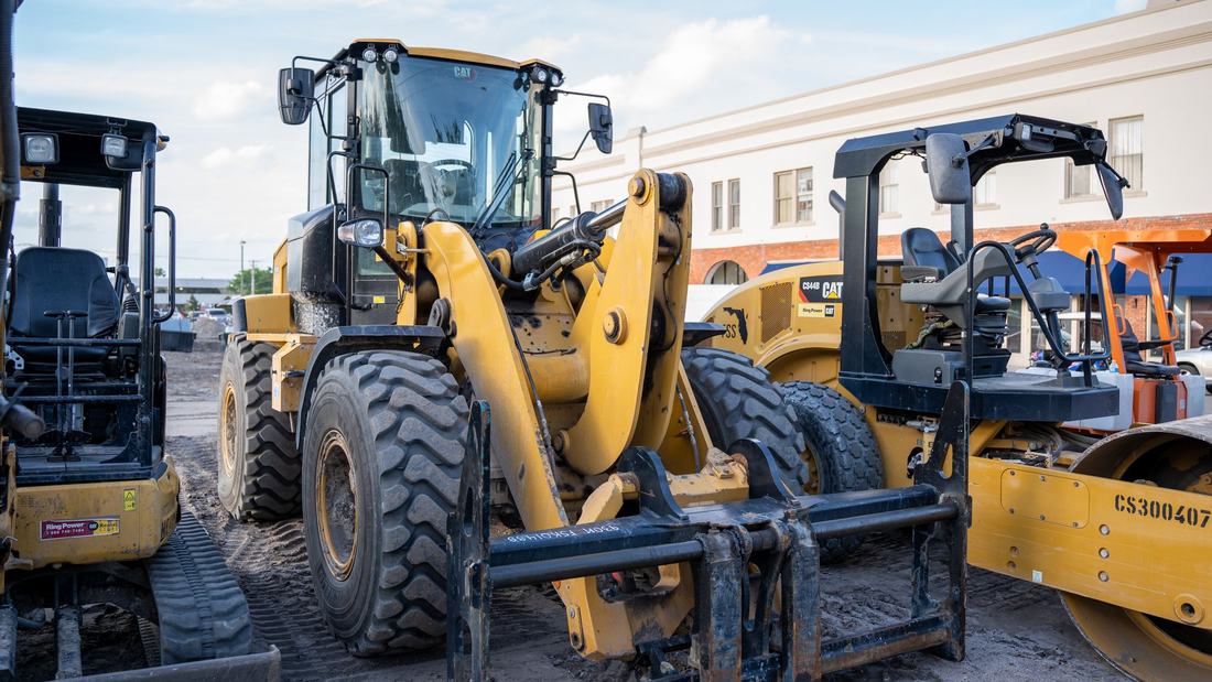Loaders and a ride-on roller parked on site, ready for compaction and loading work (illustrative stock photo)