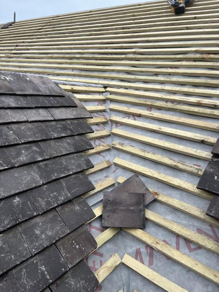 Clay plain tiles being laid on new battens