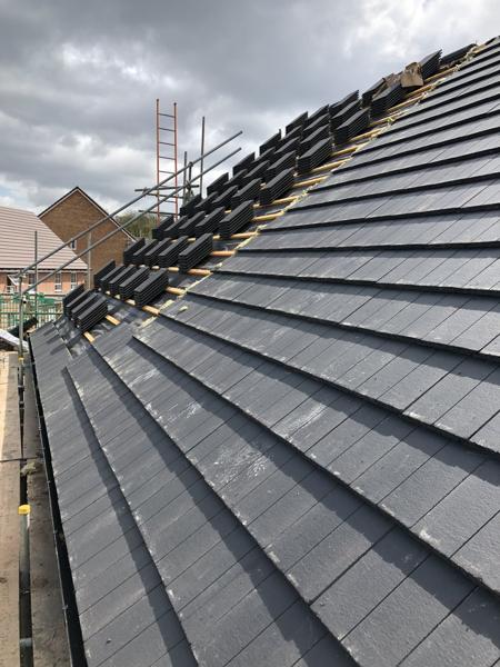 Interlocking concrete tiles being laid on a new-build roof